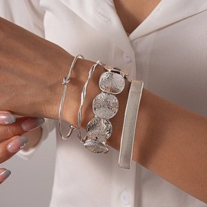 Close-up of four-piece silver geometric bracelet set with irregular knots and hammered textures