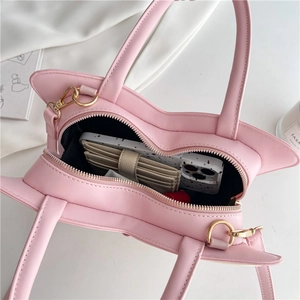 Pink heart-shaped handbag with golden hardware showing spacious interior with essentials