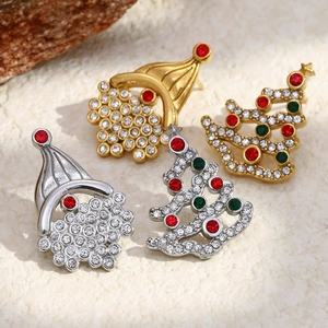 Christmas earrings in gold and silver plating with colorful rhinestones on stone background