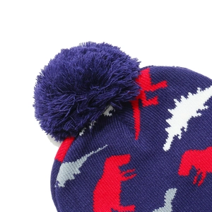Detailed close-up of navy knit beanie texture with dinosaur patterns and fluffy pompom