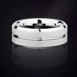 Frosted stainless steel ring with polished edges and center groove on a black surface