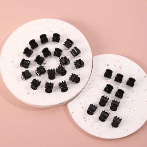 50-piece set of mini black plastic hair claws on marble display stands for styling
