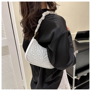 Detail of white quilted underarm bag with pleated cloud strap and golden metal buckle