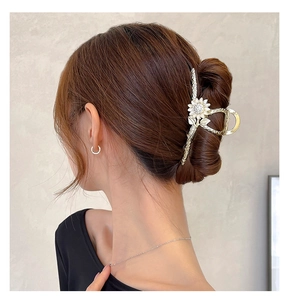 Détail de la pince à cheveux tournesol dorée avec strass dans une coiffure élégante