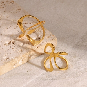 Detailed close-up of golden geometric and wavy stainless steel rings on stone texture