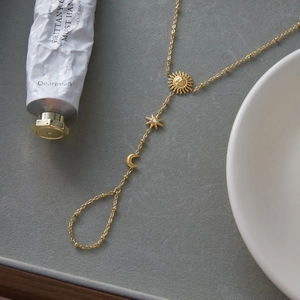 Macro view of 18K gold stainless steel finger bracelet with sun star and moon charms
