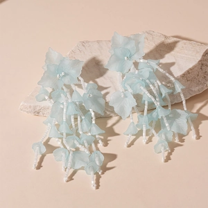 Detail of light blue floral tassel earrings with frosted acrylic petals and white beads