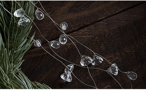 Detail of faceted acrylic icicle ornaments with silver wire on a Christmas pine branch