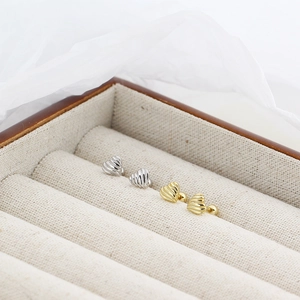 Macro detail of heart-shaped screw back earrings in textured silver and gold finish