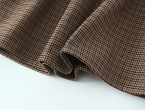 Detail of coffee plaid woven fabric showing smooth draping and soft texture of the dress