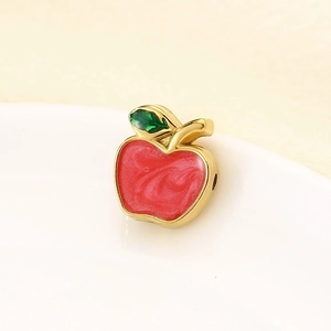 Detailed view of red and green enamel apple pendant with polished gold metal plating