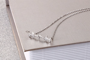 Detail of silver electrocardiogram pendant on a delicate chain over a book