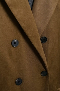 Detailed macro view of brown suede coat collar featuring four dark double-breasted buttons