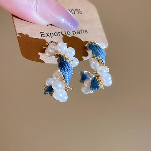 Detail of C-shaped hoop earrings with blue denim fabric wrap and white pearl accents