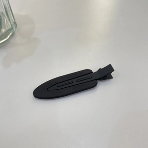 Detail shot of matte black hair clip showing smooth frosted texture and drop shape