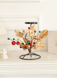 Detailed view of metal leaf decor and colorful berries on a festive Christmas candle holder
