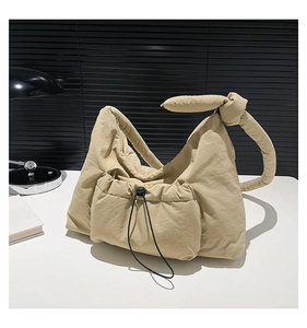 Detail of khaki nylon quilted shoulder bag featuring knot strap and drawstring front pocket