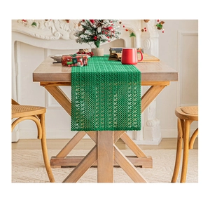 Close-up of green openwork knit table runner on wooden table with Christmas background