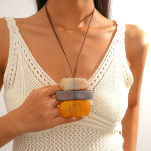 Macro view of geometric acrylic pendant with marble texture on brown suede necklace