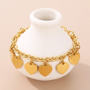 Detailed view of 18K gold plated stainless steel heart charm bracelet on a white vase