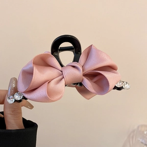 Detail of pink satin ribbon bow hair claw clip with sparkling rhinestones decoration