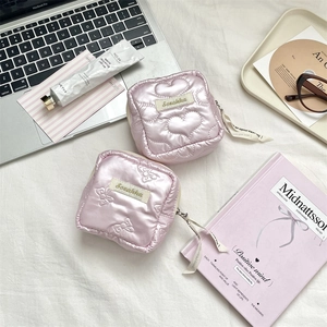 Detailed view of pink quilted heart and bow sanitary storage pouches on a desk