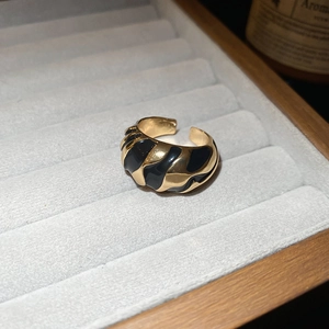 Detailed view of the wavy black enamel and gold adjustable ring in a jewelry box