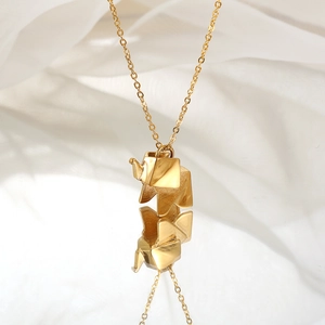 Minimalist gold origami elephant pendant necklace with mirror reflection on white fabric