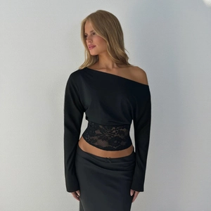 Detail of elegant black lace patchwork on the waist of a one-shoulder slim-fit top