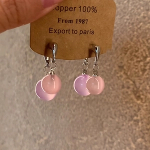 Detail of resin hoop earrings with pink and purple beads on a vintage paper card