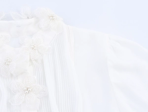 Detailansicht des weißen Chiffon-Blusenkragens mit 3D-Blumen, Perlen und Falten