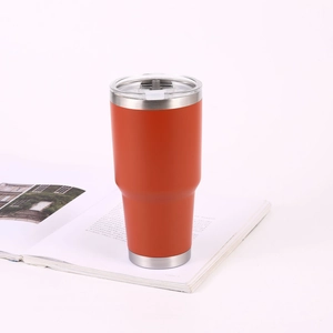 30oz orange stainless steel tumbler with clear lid on a magazine background