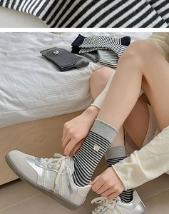 Detailansicht von gestreiften Baumwollsocken mit kleiner Bärenkopf-Stickerei am Knöchelrand