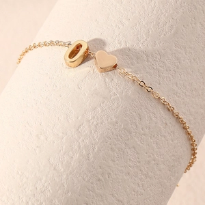 Elegant gold stainless steel bracelet with a letter O charm and heart pendant detail