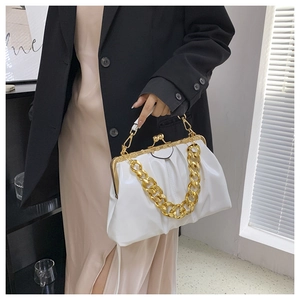 Detail of white pleated clutch bag with gold frame and chunky chain strap held by model