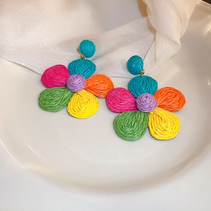 Detailed view of colorful woven flower earrings with textured raffia multi-color petals