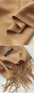Detailed macro view of khaki cashmere scarf texture with tassel and authentic label