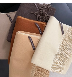 Detail view of colorful cashmere-like scarves in beige and brown with tassel accents