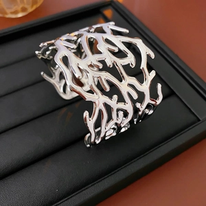 Macro shot of a silver hollow open cuff bracelet with metallic coral-inspired design