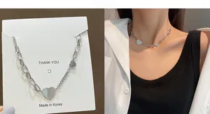 Close-up of heart pendant necklace with asymmetric chain design on display card