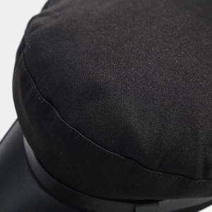Detailed view of black military cap with twill fabric and glossy peak brim texture