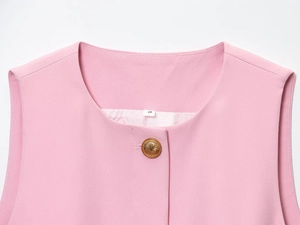 Dettaglio dello scollo del gilet rosa con bottone dorato ed etichetta taglia S