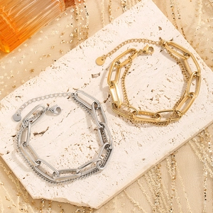 Gold and silver chunky link bracelets with round pendants on textured stone background