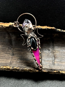 Detail of vintage bronze pendant with agate arrow and amethyst on rustic wood