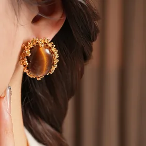Vintage French style gold stud earrings with large oval tiger eye stone on a model