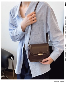Detail view of a vintage dark brown saddle bag with a golden twist lock on a model