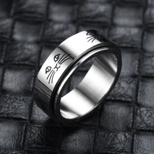 Detailed close-up of a silver rotating ring featuring engraved cartoon cat face patterns