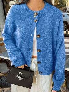 Gros plan d'un gilet en maille bleue avec boutons marron sur fond de rue urbaine