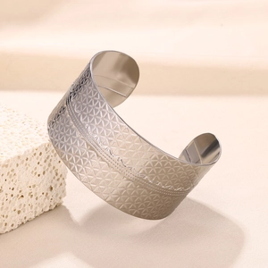 Detail showing geometric triangle texture and dotted line on wide silver stainless steel cuff