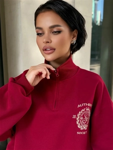Detail eines burgunderroten Half-Zip-Sweatshirts mit authentischem Society-Brustdruck